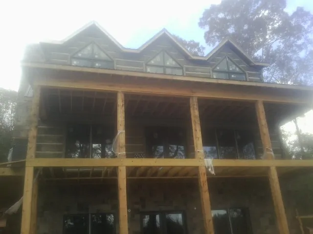 Dormers and porch framing on a large log home under construction — Roof Coating work by our crew in Fruitland