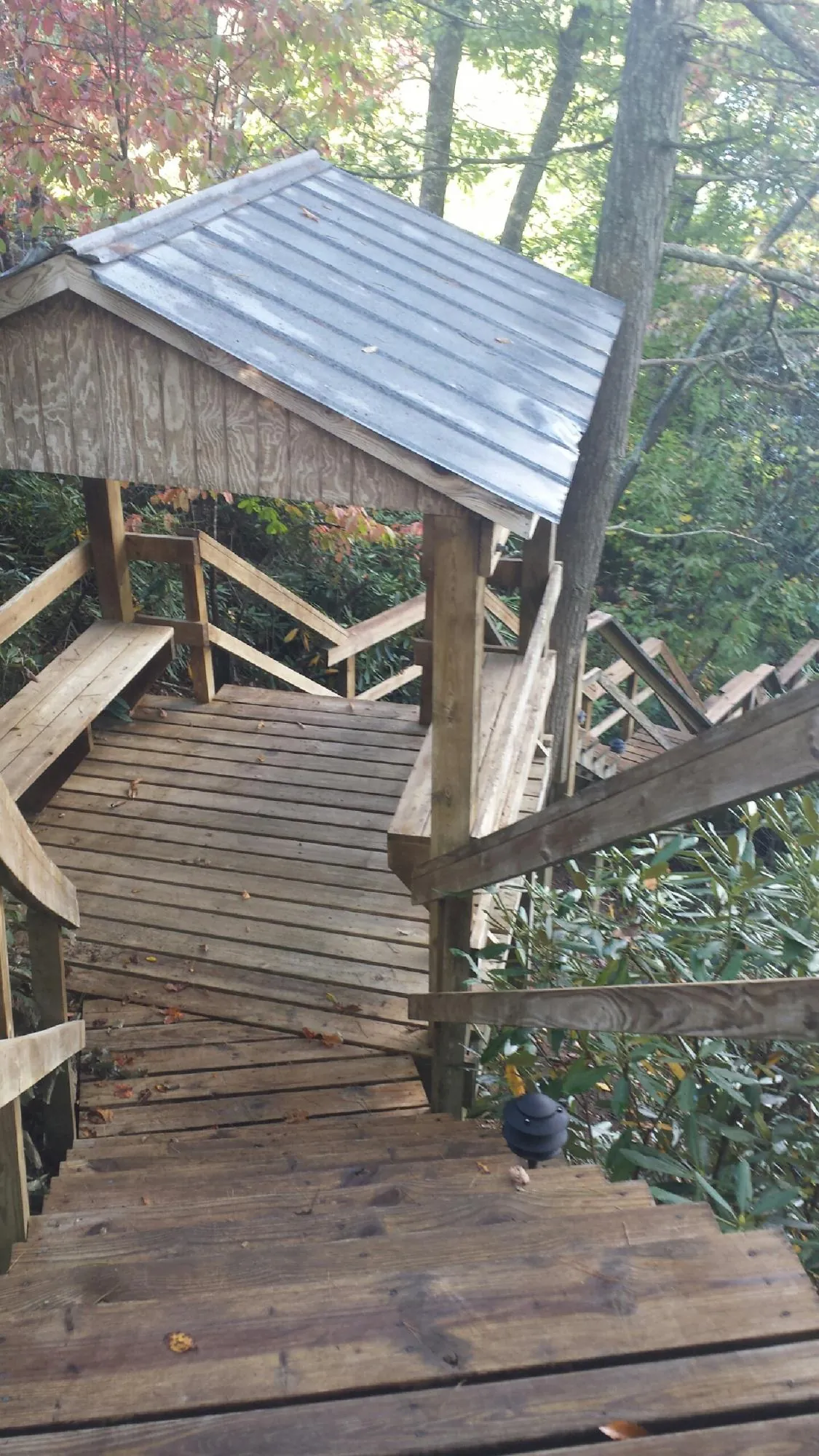 Metal roofed shelter over wooden steps on a wooded walkway — Skylight Repair & Installation work by our crew in Fruitland